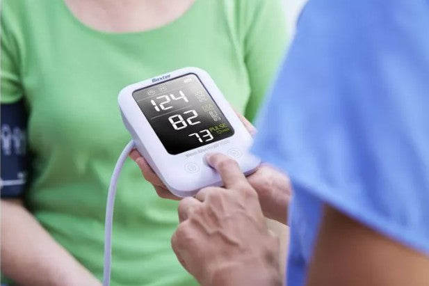 Person using a Welch Allyn ProBP blood pressure monitor with a digital display.