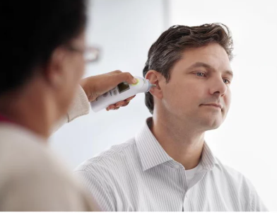 Person applying a thermometer to another person's hair with a white background